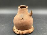 a small clay vase with a handle on a table