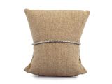 un bracelet en diamants posé sur un coussin, sur fond blanc