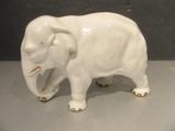 porcelain figurine of an elephant on a table with a gray background