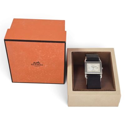 une boîte orange contenant une montre, posée sur une surface blanche