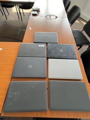 Plusieurs ordinateurs portables sont alignés sur une table dans une salle de réunion