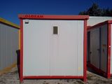 two portable toilets in the middle of a dirt field