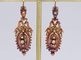 pair of earrings on a gold stand with a white background