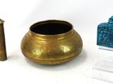 un vase en or et une bouteille en verre bleue placés l'un à côté de l'autre