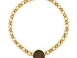 Gros plan sur un bracelet en chaîne en or sur lequel se trouve une pièce de monnaie