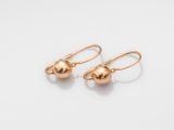 une paire de boucles d'oreilles en forme de boules dorées sur fond blanc