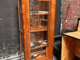 a wooden cabinet with a glass door in front of a brick wall