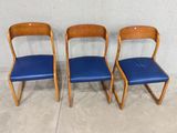 three blue leather chairs sitting next to each other in front of a wall