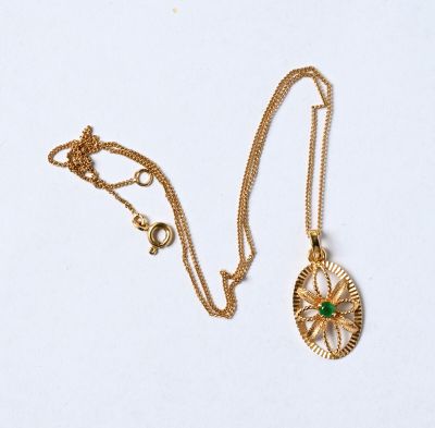 un collier en or avec un pendentif en pierre verte et une chaîne en or