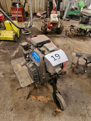 Plusieurs tondeuses à gazon sont garées dans un garage, avec une plaque d'immatriculation à l'avant.