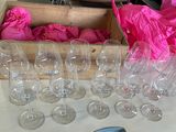 Plusieurs verres à vin vides sont posés sur une table, à côté d'un sac rose.