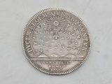 a silver coin with a sun and stars on it