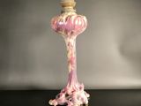 pink and white vase with a crown on top on a table