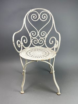 an old white iron chair with a heart design on the back