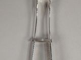 a silver spoon and tonget on a white surface