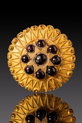 deux paires de boutons en verre doré et noir sur une surface réfléchissante