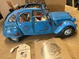 a blue toy car sitting on a table next to a brown bag