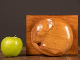 a wooden sculpture of a cat and an apple on a table