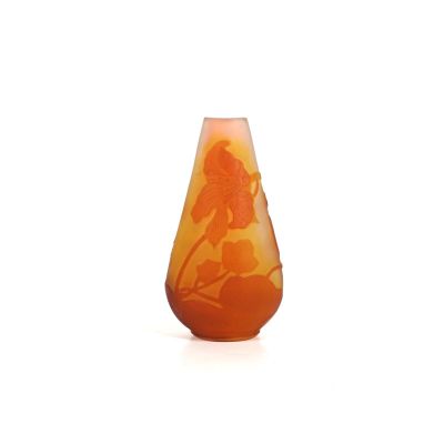un vase orange orné d'une fleur, posé sur une surface blanche