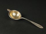 a silver spoon with a metal strainer on top of it