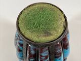 a blue vase with a green top sitting on a white surface