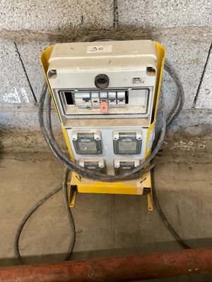 a yellow and white machine sitting on top of a cement floor next to a wall