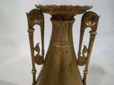 un grand vase en laiton avec deux anses sur une table