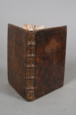 an old book with a brown cover sitting on top of a table