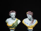 three porcelain busturines of women on pedestals against a black background
