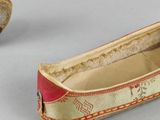 pair of shoes with red and gold trims and a red and gold slipper
