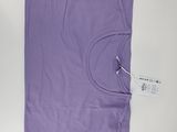 La chemise violette est posée sur une surface blanche, à côté d'une paire de ciseaux.
