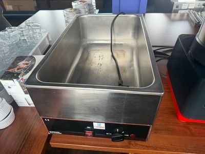 un évier en acier inoxydable posé sur une table à côté d'une cafetière