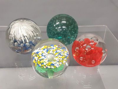 four different colored glass balls on display in a clear box