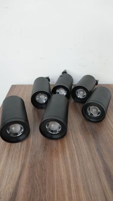 six projecteurs à LED noirs posés sur une table en bois, devant un mur blanc