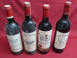 four bottles of wine are lined up on a red cloth