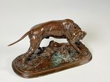 statue en bronze représentant un chien assis sur un rocher, tenant un oiseau dans la gueule