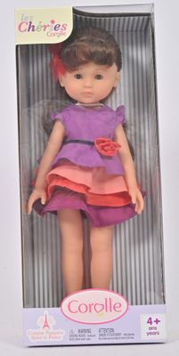 poupée dans une boîte, vêtue d'une robe rose et violette et d'un nœud rouge