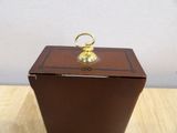 a small wooden box with a brass ring on top of it