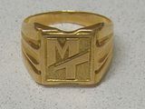 une photo d'une bague en or sur laquelle figure la lettre « m »