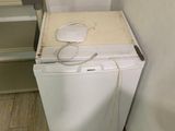 an image of a small white refrigerator in a small room