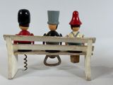 three figurines sitting on a wooden bench