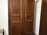 a large wooden armoire in the corner of a room with pots and pans