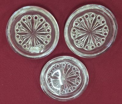 trois dessous de verre en verre posés sur un tissu rouge, sur fond rouge
