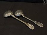 pair of silver spoons on a black cloth with a black background