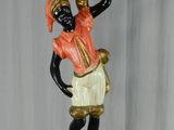 statue of a woman holding a pot on her head on a wooden base