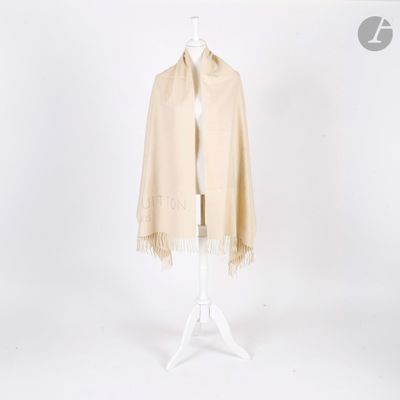 un mannequin blanc portant un châle beige, posé sur un socle blanc