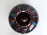 a close up of a black and red vase on a white surface