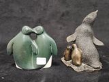 two figurines of penguins sitting next to each other on a black background