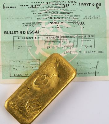 un lingot d'or posé à côté d'un passeport sur une table