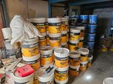 several buckets of paint are stacked on top of each other in a garage